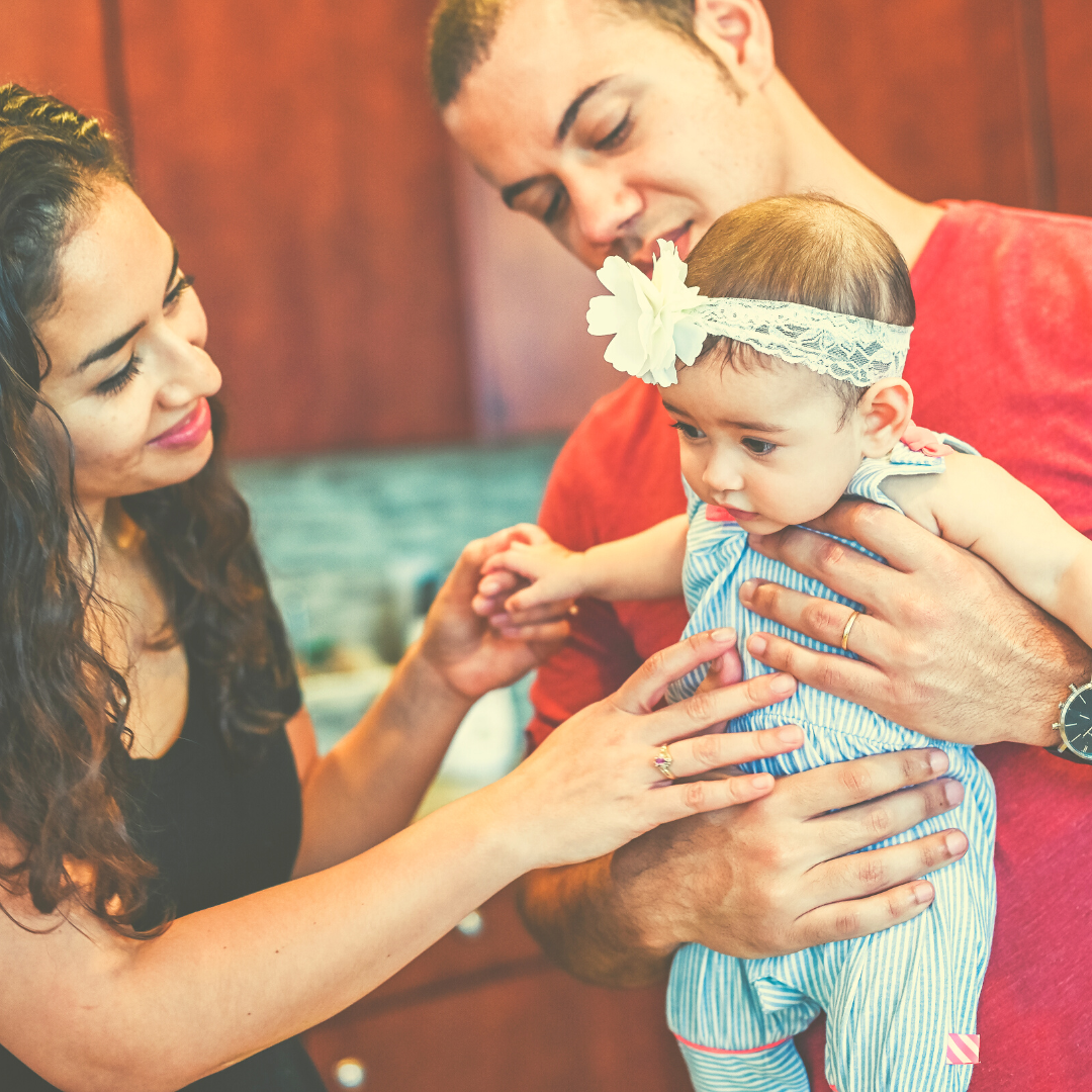 Latino parents holding a baby girl and smiling